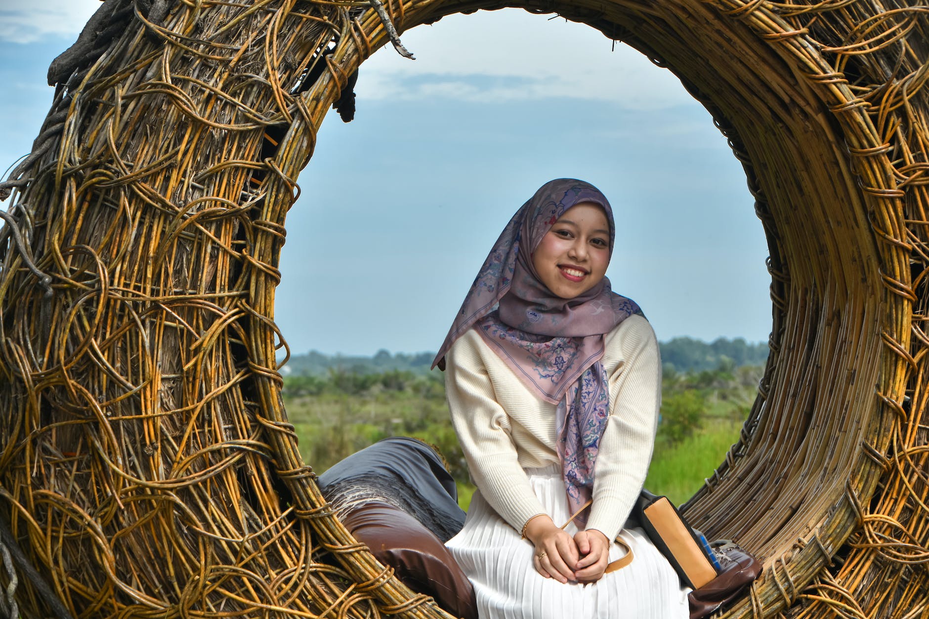 smiling young woman in a headscarf sitting on a wicker circle bench